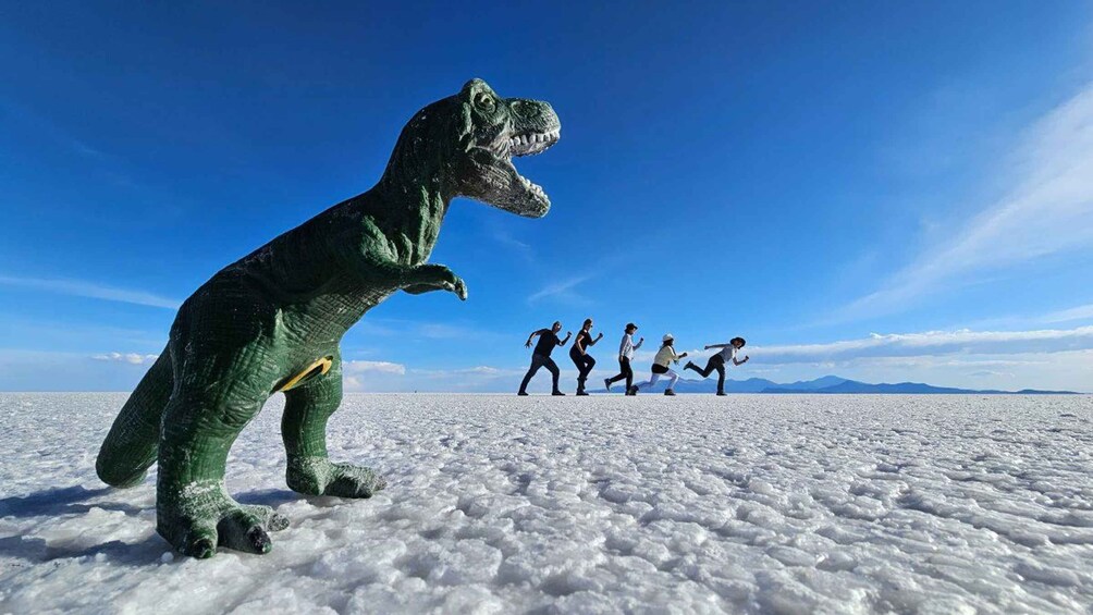 A dinosaur model on a snowy plain with a clear blue sky. 5