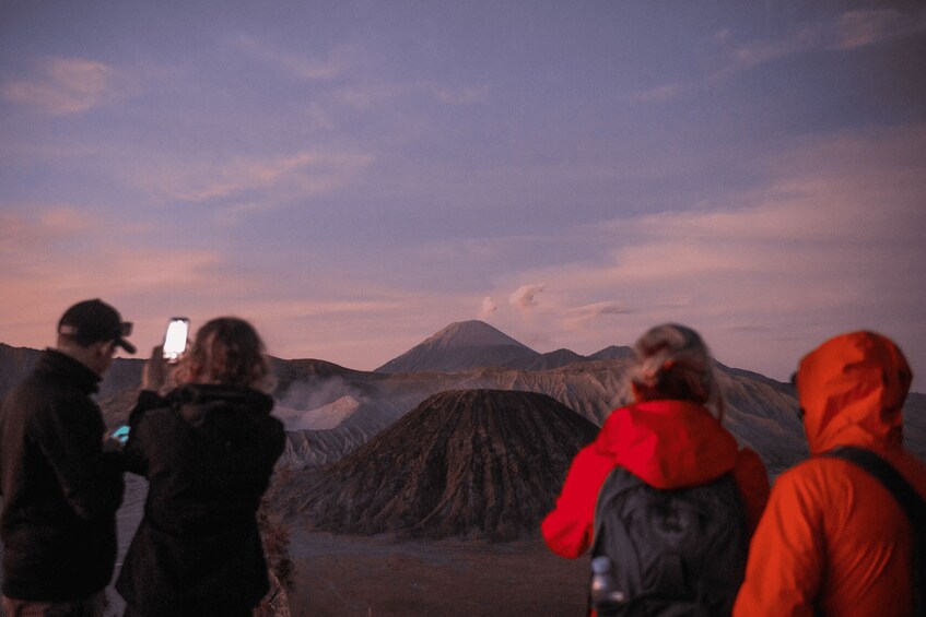 A group of people standing on a mountain with a volcano in the background. 2