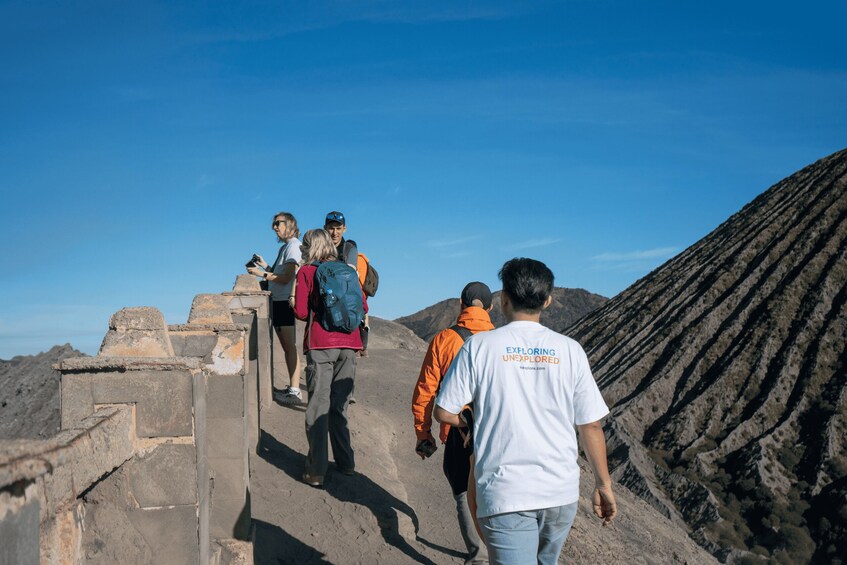 A group of hikers ascending a rocky path with a mountainous landscape in the background. 3