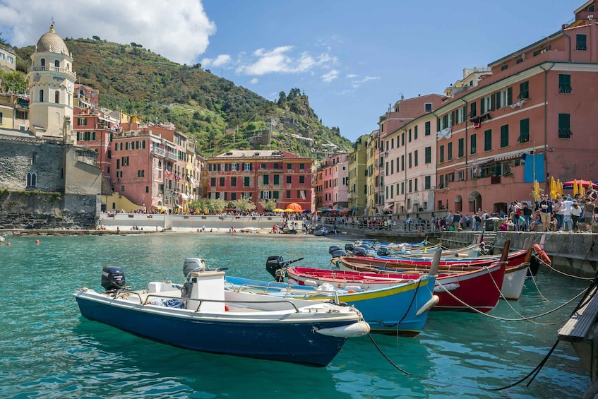 A coastal town with colorful buildings, boats docked along the waterfront, and a hill with a church in the background. 5