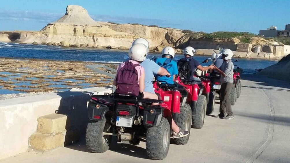 A group of people on quad bikes near a coastal area with rocky cliffs. 4