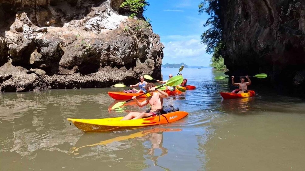 People kayaking in a river with rocky cliffs on both sides. 2