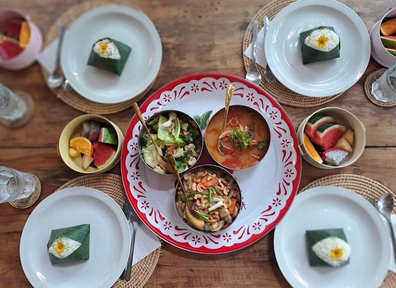 A table with various dishes, including rice wrapped in leaves, a bowl of soup, and a plate of mixed vegetables. 5