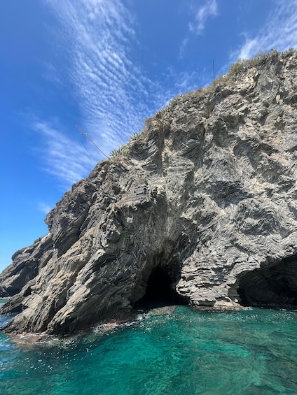 A rocky coastline with a cave entrance and clear turquoise water. 3