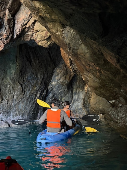Two people kayaking in a narrow waterway with rocky walls. 2