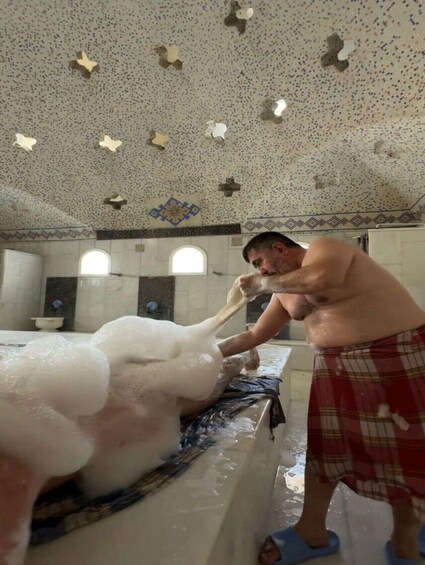 A man in a bathroom with a large amount of foam. 2