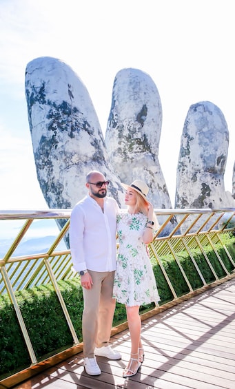A couple standing on a wooden deck with large rock formations in the background. 3