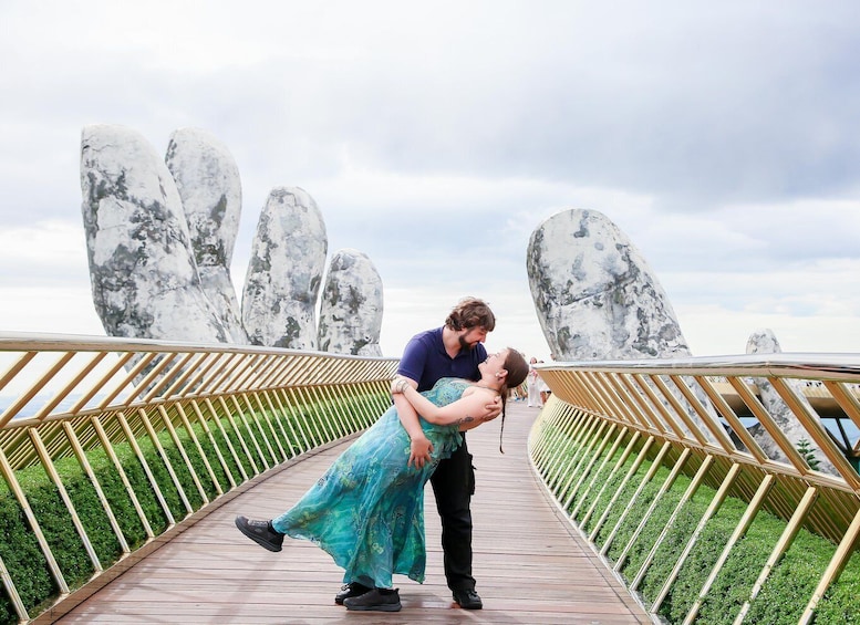 A couple embracing on a wooden bridge with large rock formations in the background. 1