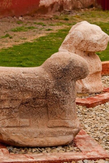 Two stone sculptures of lions on a gravel path. 3