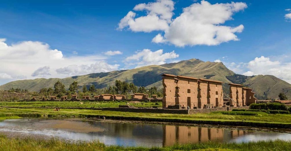 A traditional building with a river in the foreground and mountains in the background. 1