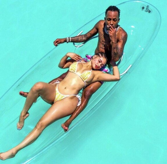 A person lying on a transparent tube in a pool. 1