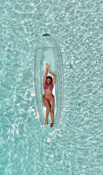 A person lying on a transparent inflatable raft in a body of water. 4