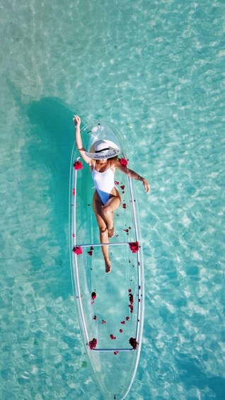 A person on a transparent raft floating on clear turquoise water. 2