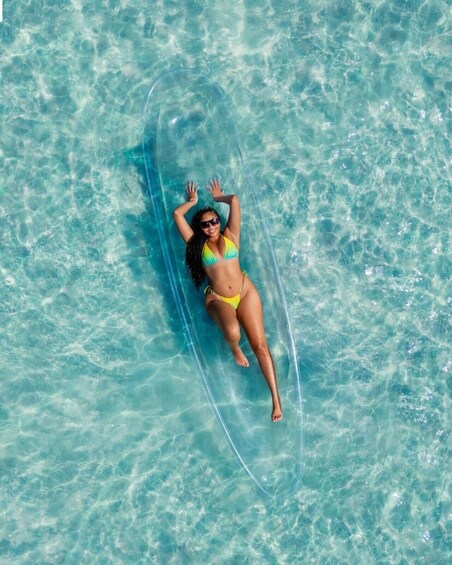 A person lying on a surfboard in clear blue water. 5