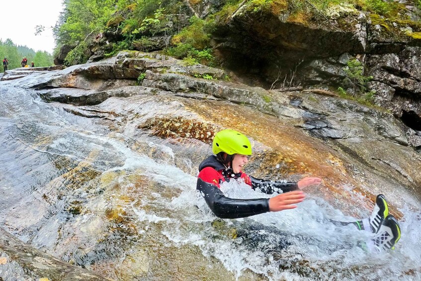 A person in a wetsuit and helmet navigating a rocky water stream. 4