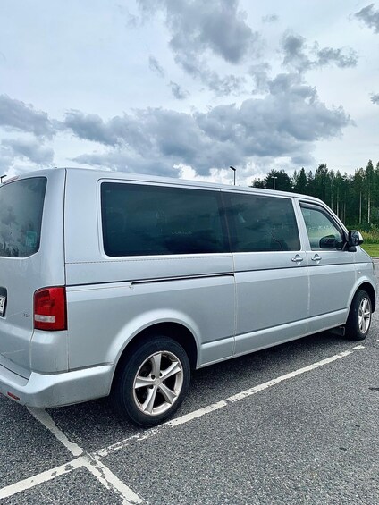 A silver van parked in a parking lot with a cloudy sky in the background. 3