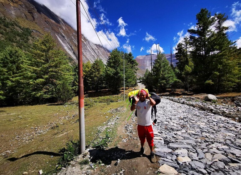 A hiker with a backpack walking on a rocky path surrounded by trees and mountains. 4