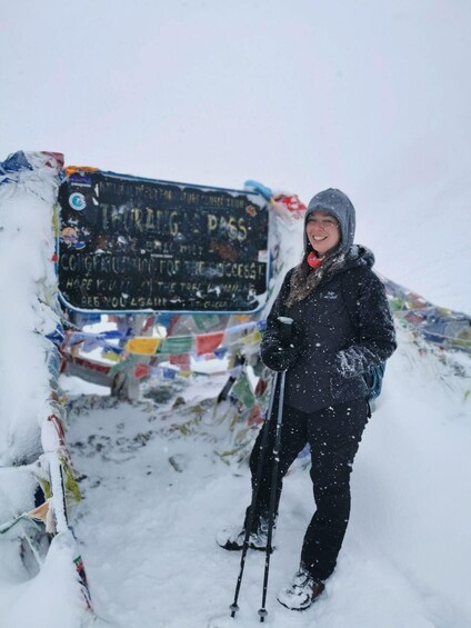 A person standing in the snow with a sign behind them. 1