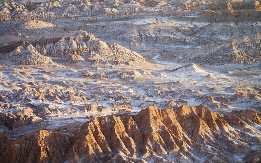 A vast desert landscape with rugged, eroded hills and valleys. 1