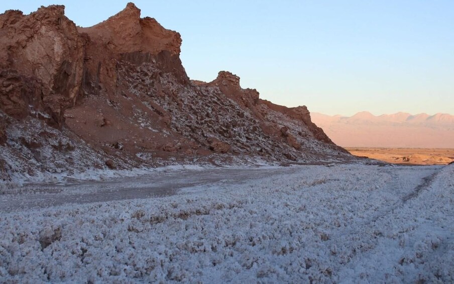 A snow-covered desert landscape with rocky cliffs and a clear sky. 3