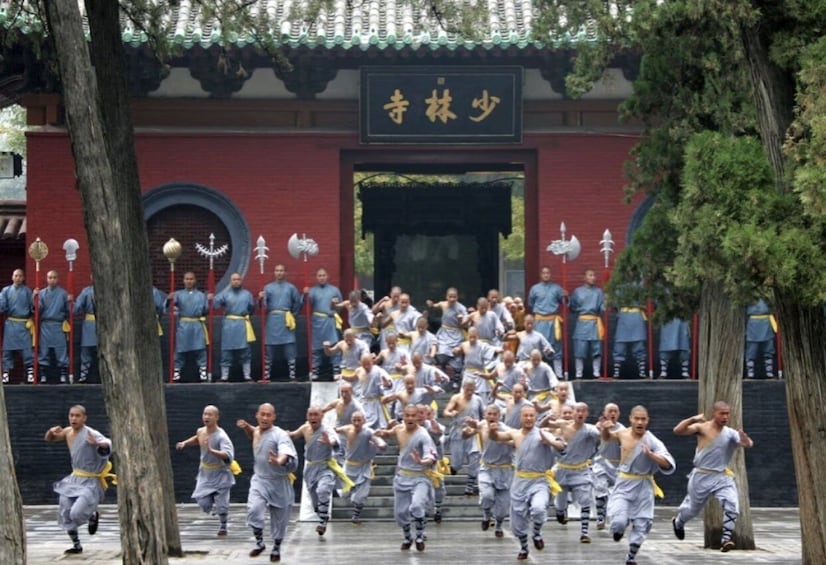 A group of martial artists performing in front of a traditional building with a sign. 1