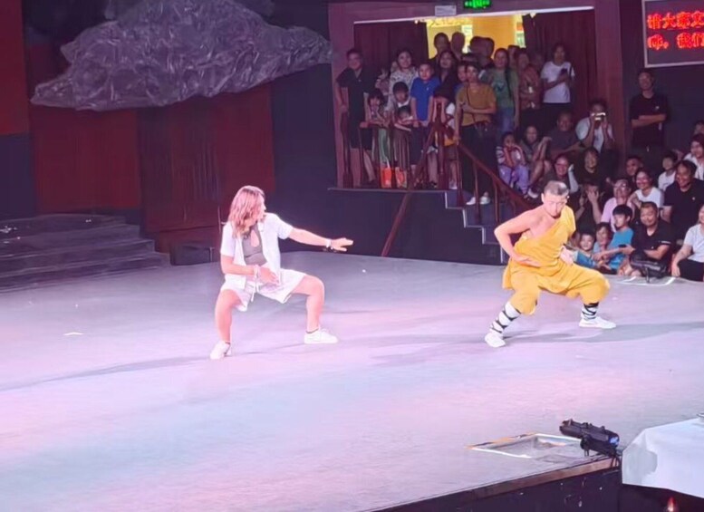 Two dancers performing on stage with an audience in the background. 4