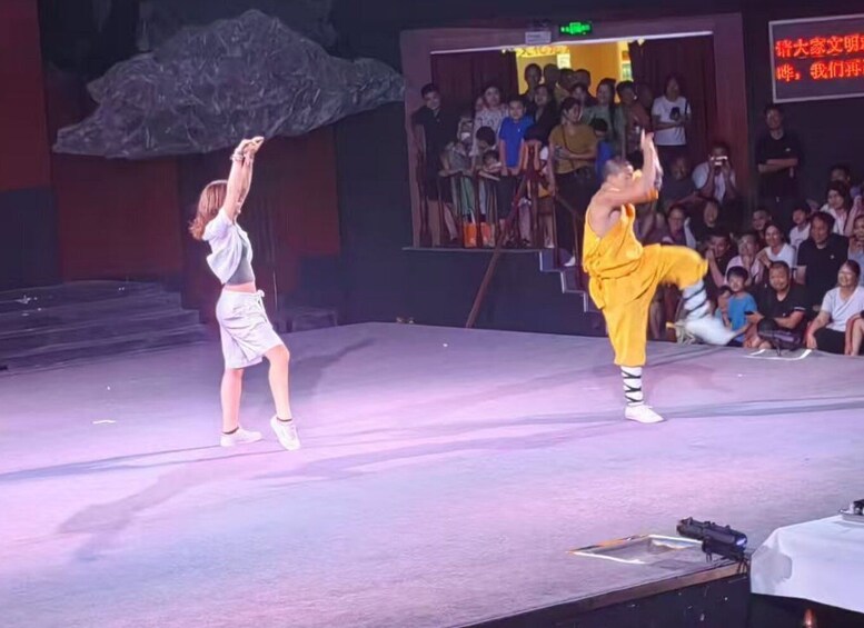 Two performers on stage, one in white and the other in yellow, executing a martial arts routine. 3