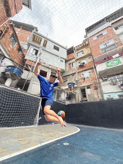 A person playing soccer on an outdoor court surrounded by buildings. 1