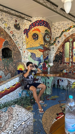 A person sitting on a bench in a room with mosaic walls and ceiling. 2