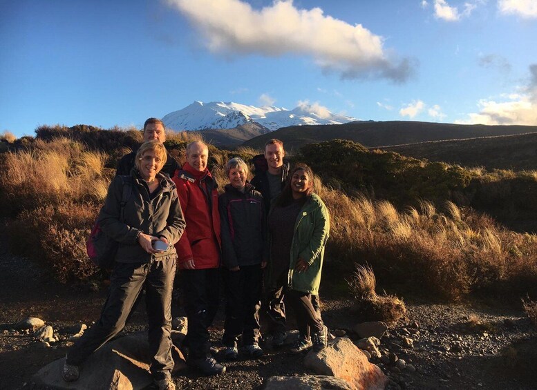 A group of people standing on a rocky path with a snow-capped mountain in the background. 2