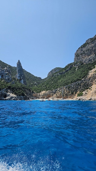 A coastal landscape with clear blue waters, rocky cliffs, and a prominent rock formation. 2