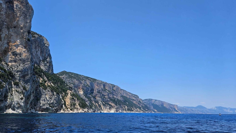 A coastal cliff with a clear blue sky and calm sea. 4