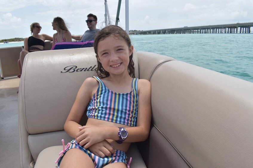 A person in a striped swimsuit sitting on a boat with a pier in the background. 5