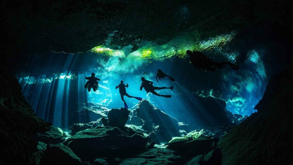 Buceadores exploran una cueva submarina con luz solar filtrándose. 1