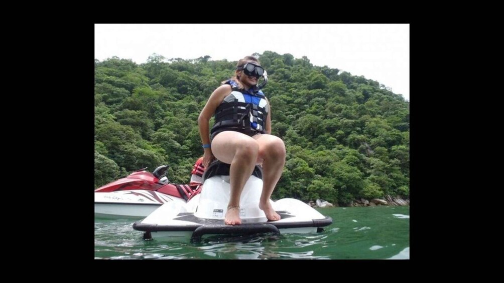 A person on a jet ski in a body of water with a forested hill in the background. 3