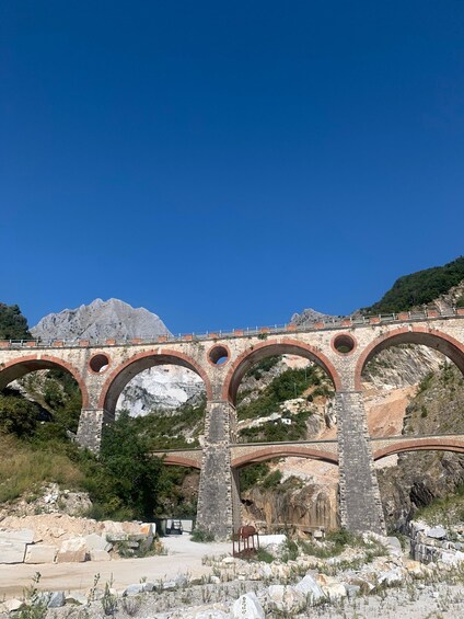 A stone bridge with multiple arches over a rocky landscape. 4