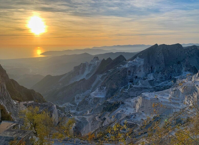 A mountainous landscape with a sunset, rocky terrain, and sparse vegetation. 1