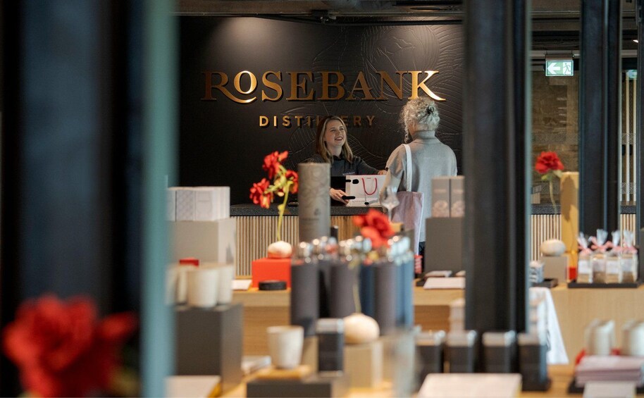 A Rosebank Distillery interior with a counter, various bottles, and a statue. 3