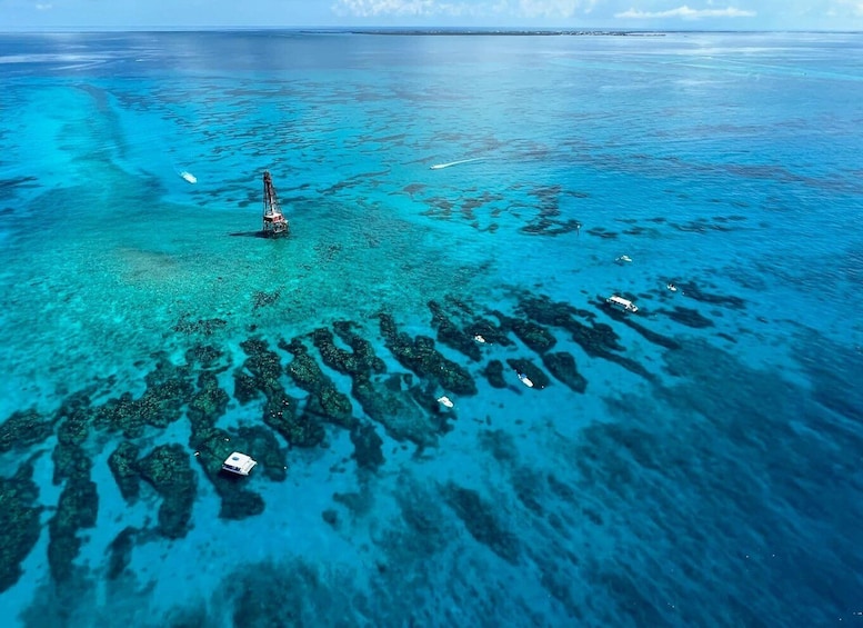 A clear blue sea with a boat anchored near a coral reef. 1