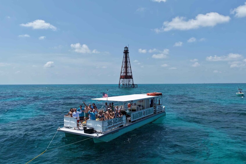 A boat named 'Marathon Mermaid' with people on board, sailing on turquoise waters with a lighthouse in the background. 3