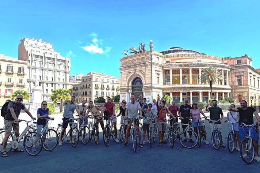 A group of people on bicycles in front of a historic building. 3