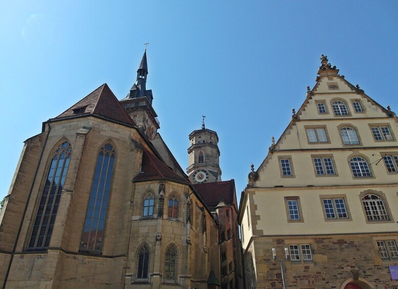 A church with a tall steeple and a clock tower, adjacent to a multi-story building with arched windows. 2