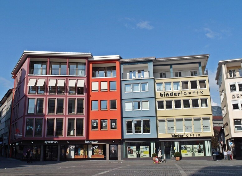 A row of colorful buildings with storefronts, including a binder optics store. 3