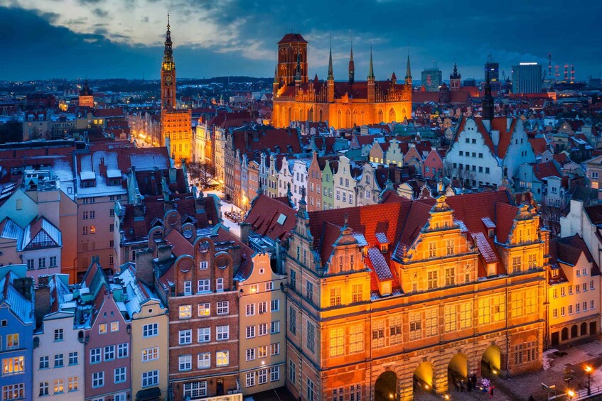 A cityscape at dusk with historic buildings and a prominent church tower. 1
