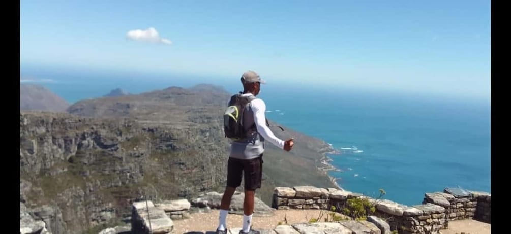 A person standing on a rocky outcrop overlooking a coastal landscape. 2