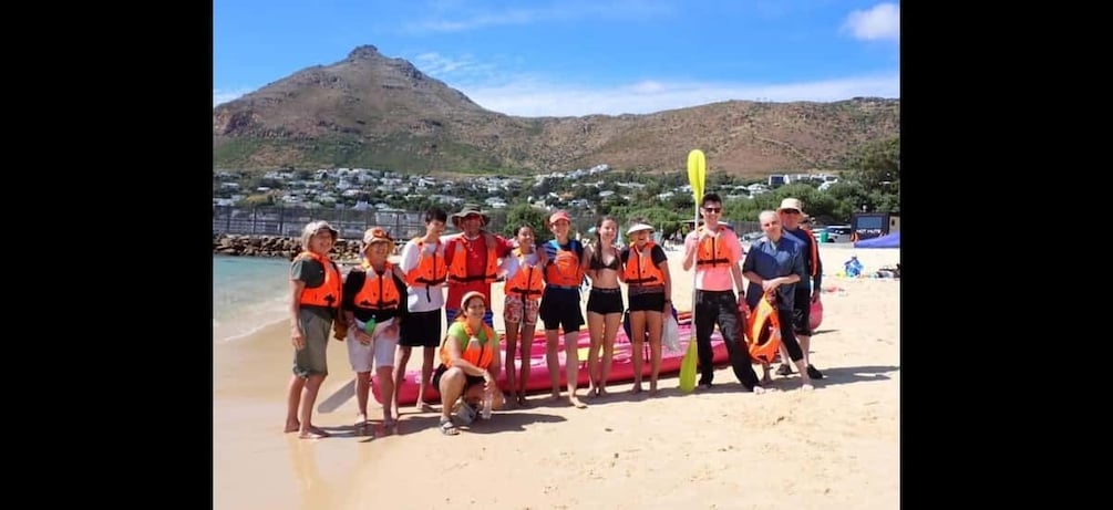 A group of people on a beach with a mountain in the background. 3