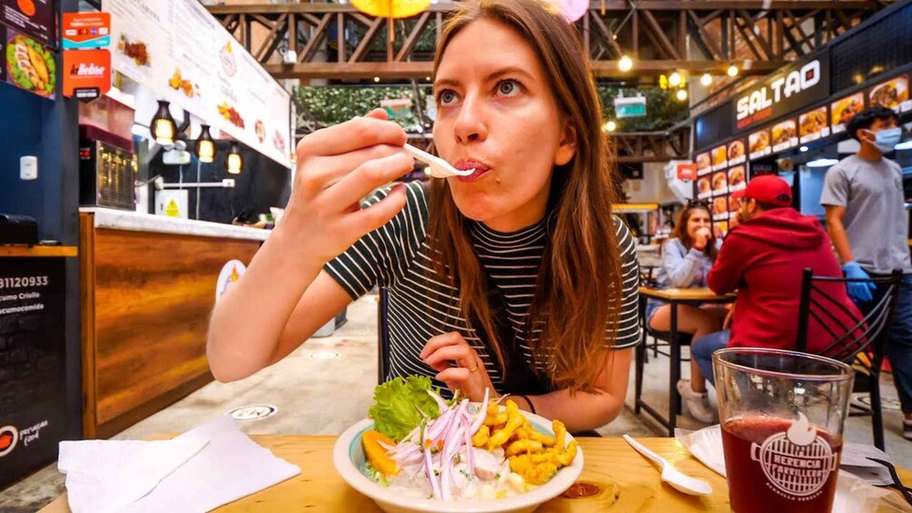 A person eating at a restaurant with a plate of food, a drink, and a menu in the background. 3
