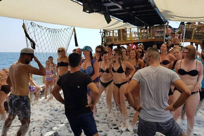 A group of people on a beach, some in swimwear, under a canopy. 2