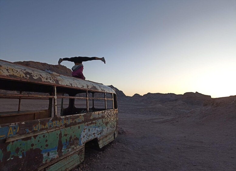 A person performing a handstand on a rusted bus in a desert landscape. 2