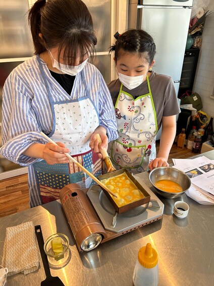 Two people cooking, one stirring a pot with chopsticks and the other holding a bowl. 5